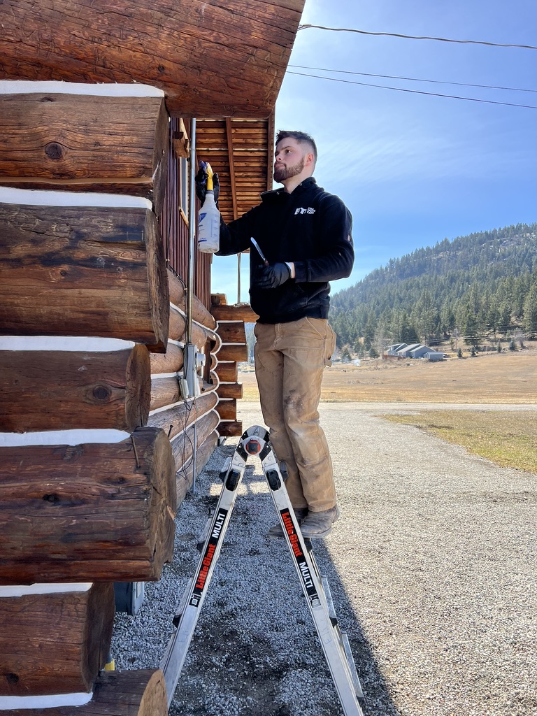 Pacific Home Renewals crew member applying stain on ladder